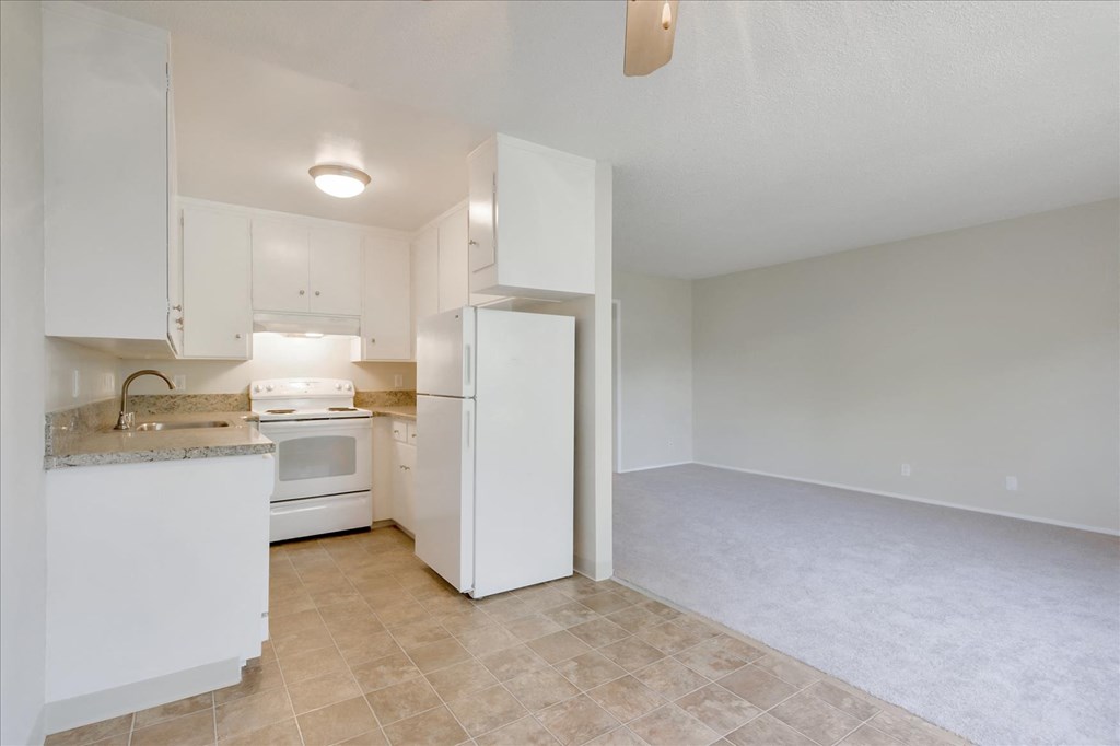 an empty kitchen with white cabinets and a white refrigerator