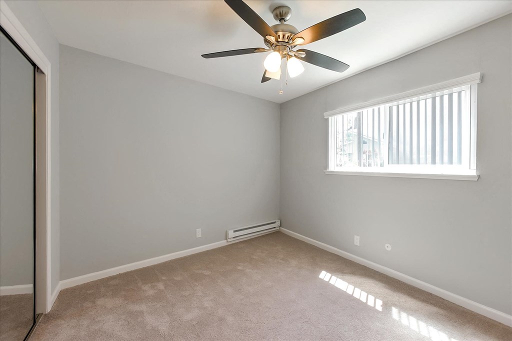 A room with a ceiling fan and a window with blinds.