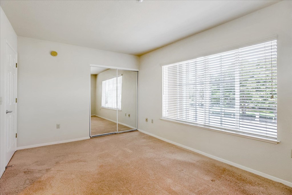 a spacious living room with a large window and a mirror
