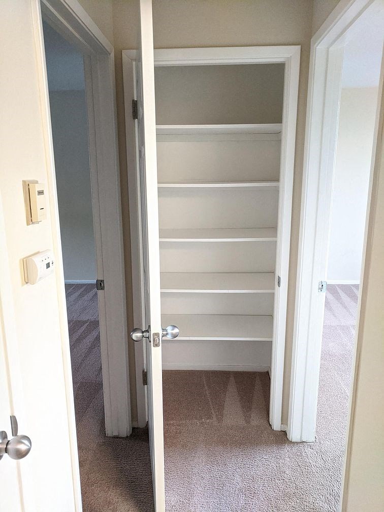 a closet with empty shelves and a door open