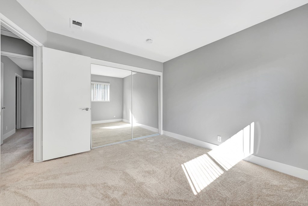 A room with a white door and a carpeted floor.