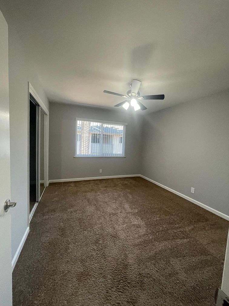 an empty room with a ceiling fan and a window