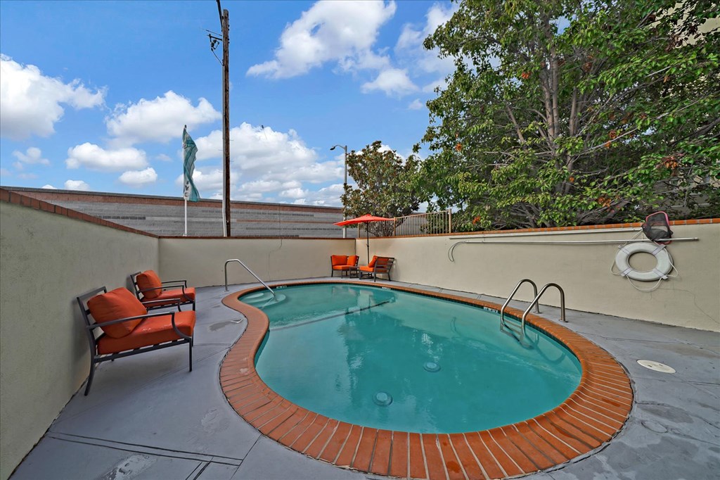 A small round pool with a brick border and a chair.