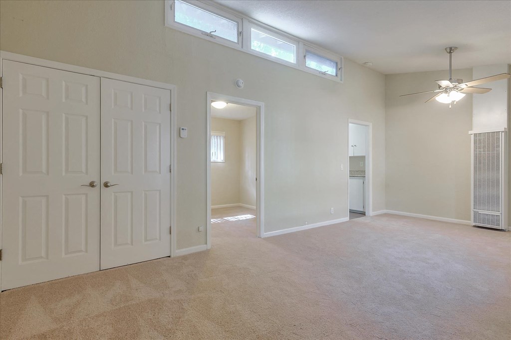 an empty living room with a closet and a ceiling fan