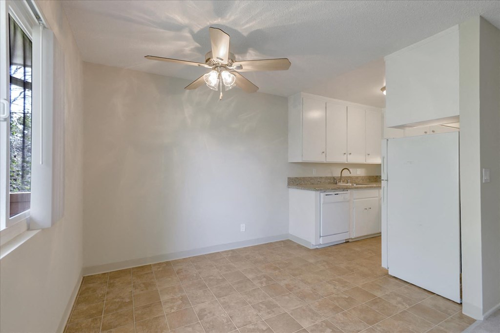 an empty kitchen with a ceiling fan and a window