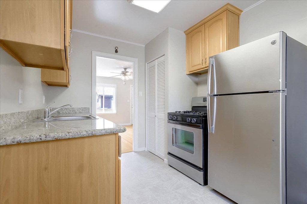 A kitchen with a refrigerator, oven, and sink.