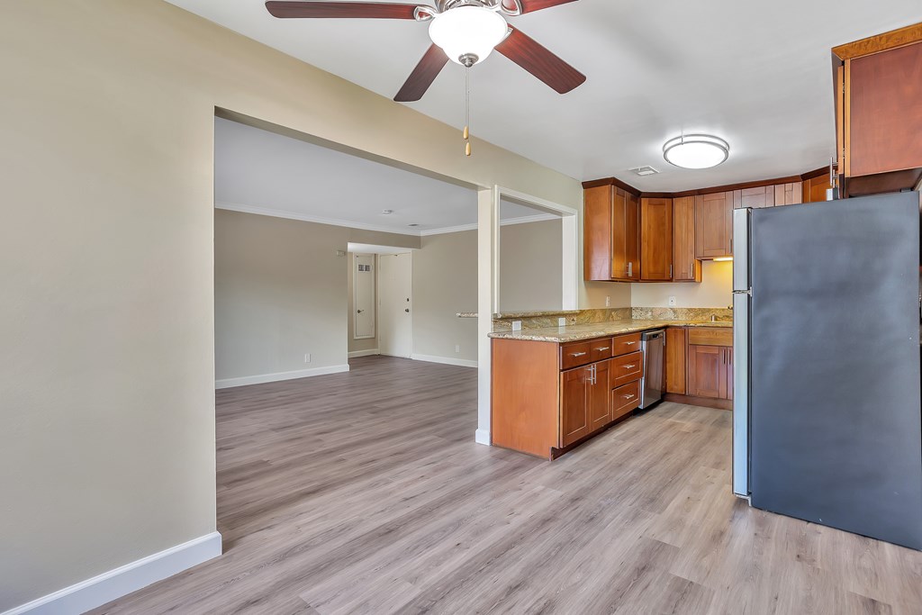 A kitchen with wooden cabinets and a black refrigerator.