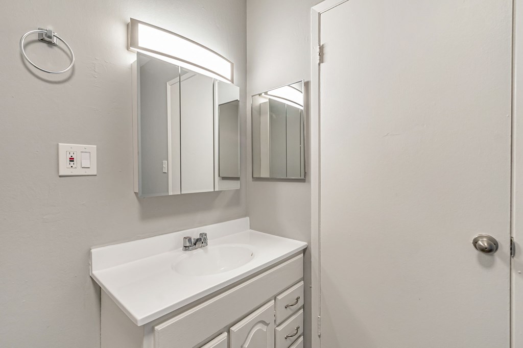 A white bathroom with a sink and mirror.