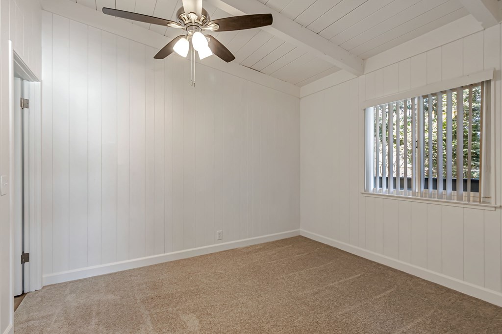 A room with a ceiling fan and a window with blinds.