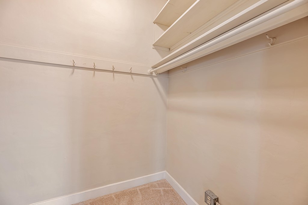 A white wall with a light switch and a white ceiling with a vent.