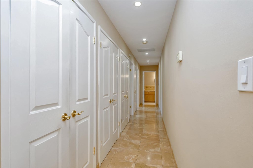 a long hallway with white closets and a tile floor