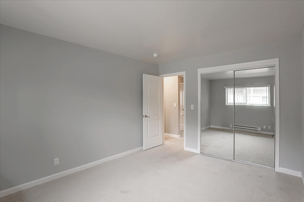 A room with a white door and a mirror on the wall.