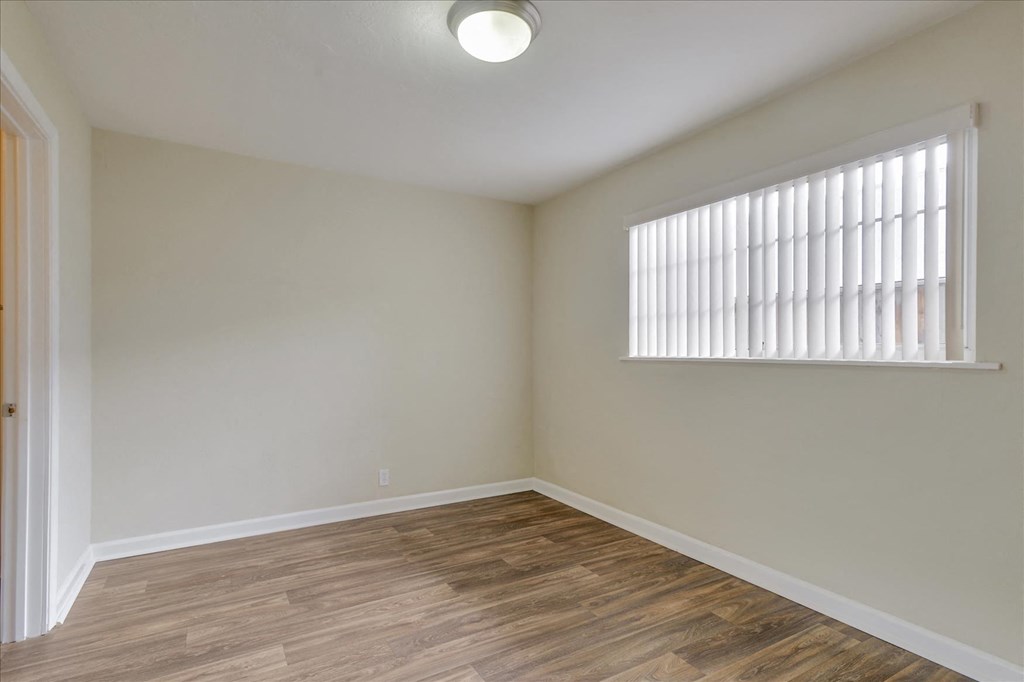 an empty living room with a large window and wood flooring