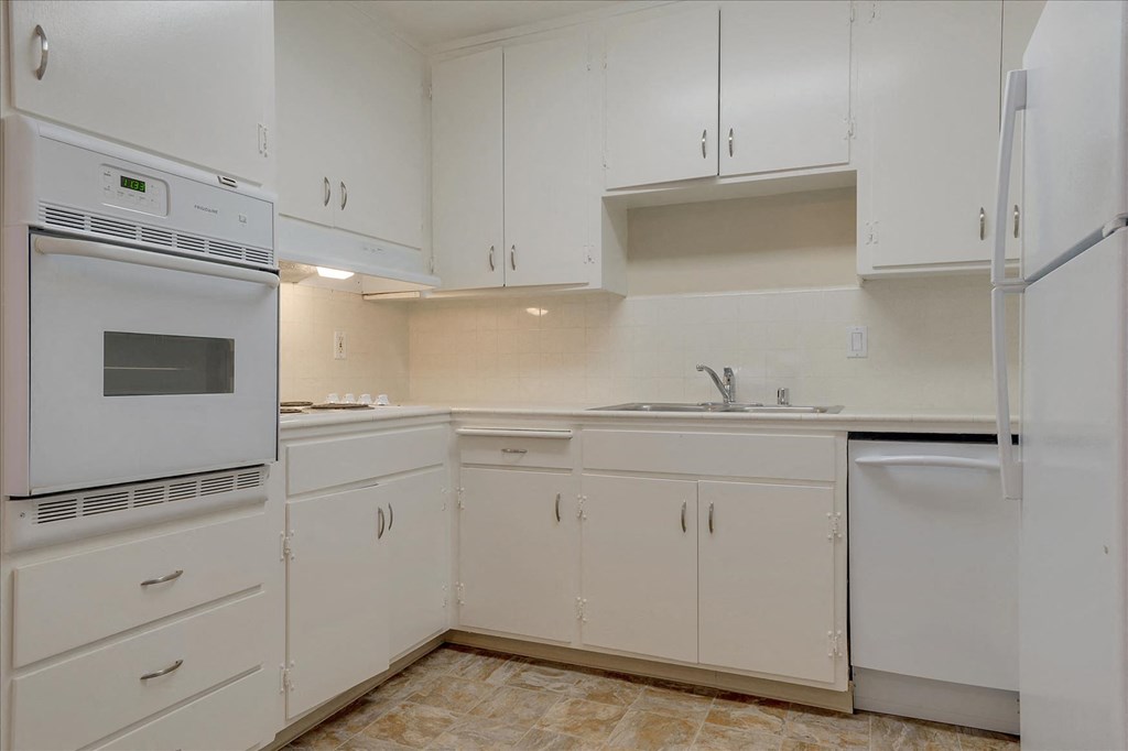 A kitchen with white cabinets and appliances.