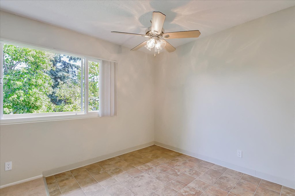 a living room with a large window and a ceiling fan