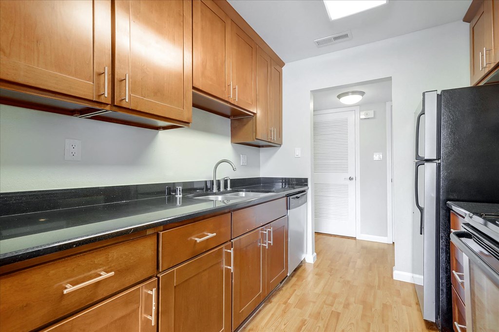 a kitchen with wooden cabinets and a black counter top and a refrigerator