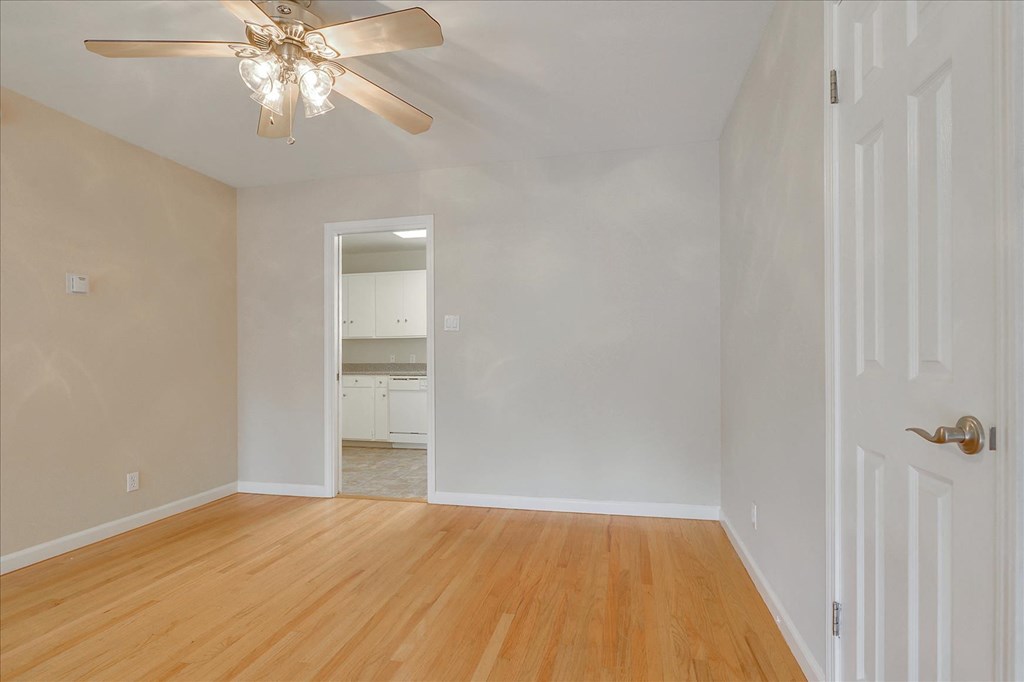 an empty living room with wood floors and a ceiling fan