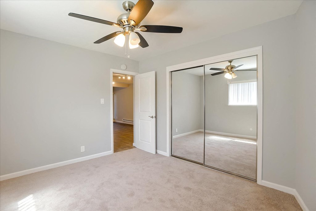 A room with a ceiling fan and a sliding glass door.