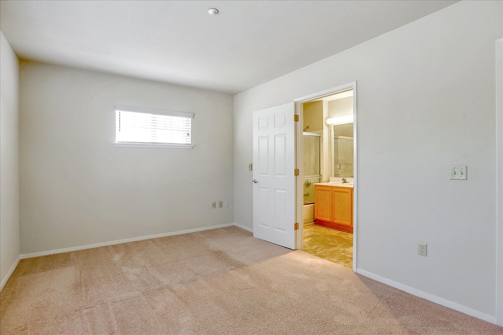 A room with a carpeted floor and a door leading to another room.