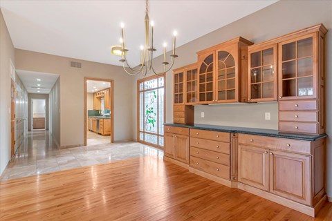 a kitchen with wood floors and cabinets and a chandelier