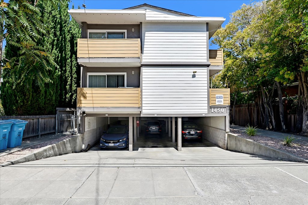 an apartment building with two cars parked in a parking lot