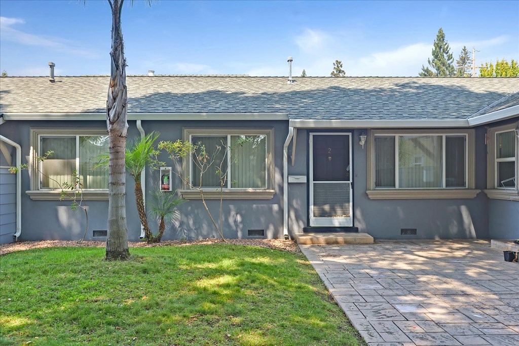 a blue house with a front yard and a tree