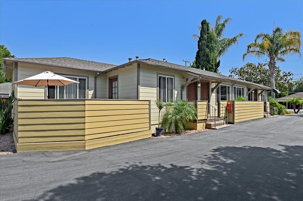 A yellow house with a brown roof and a red door.