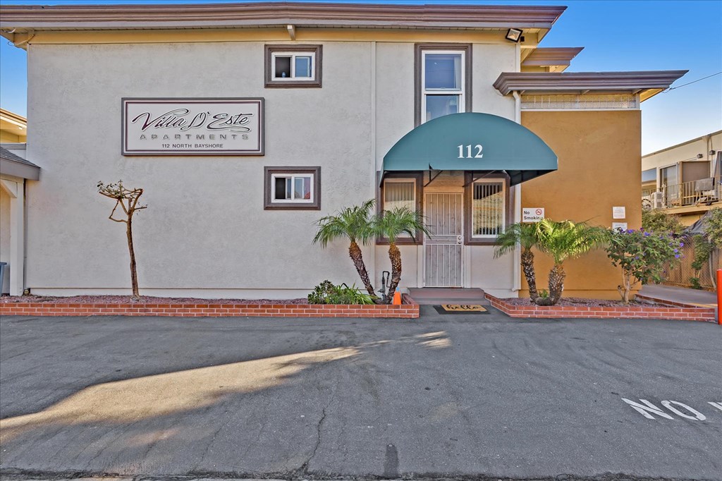 the front of a building with a blue awning and palm trees