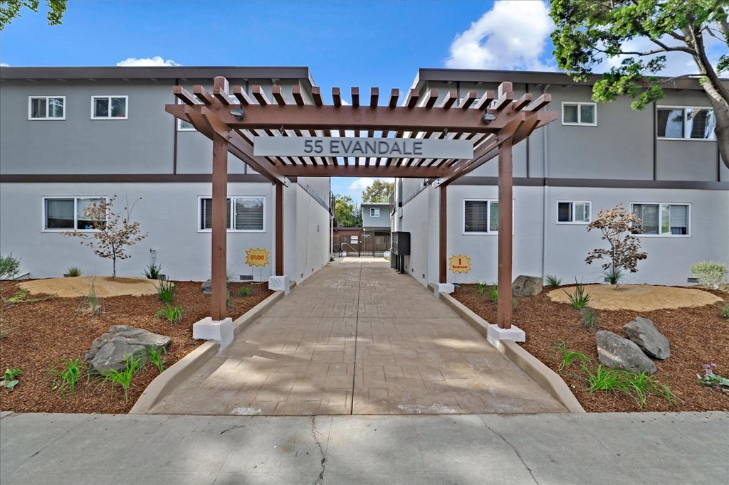 a sidewalk in front of a building with a wooden archway