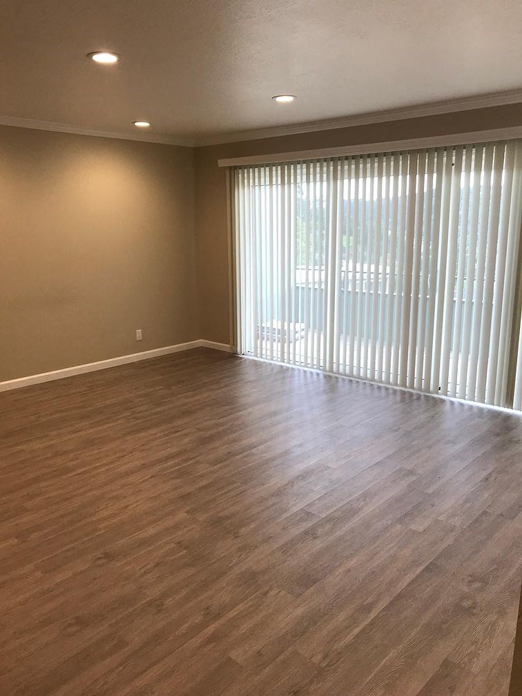 A room with wooden flooring and a window with blinds.