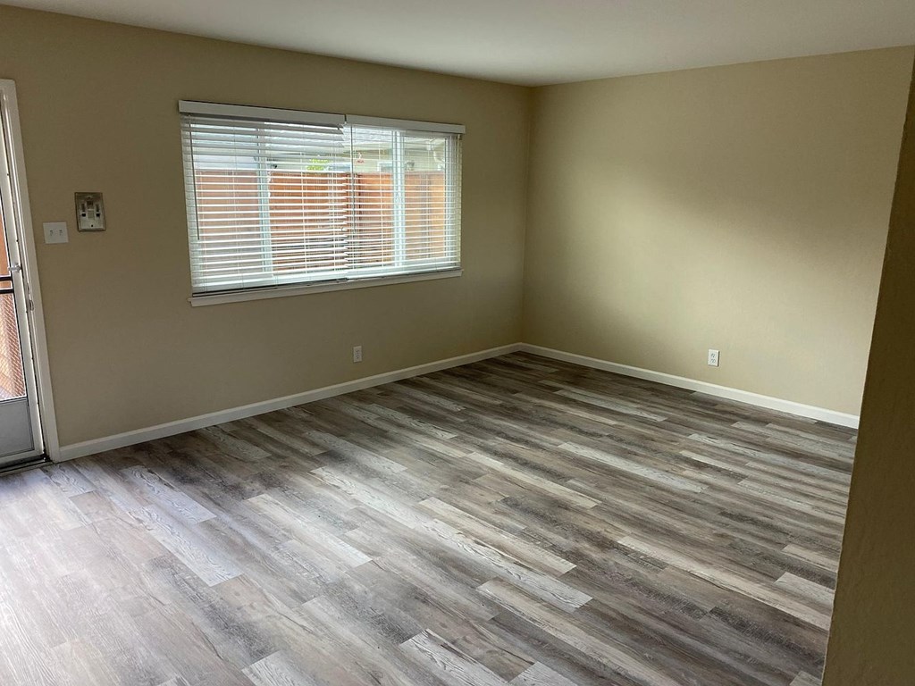 A room with a window and wooden flooring.