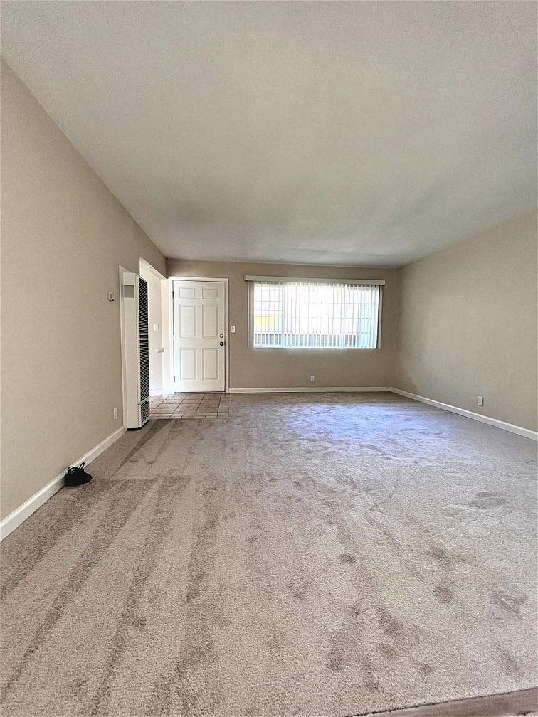 A room with a carpeted floor and a door leading to another room.
