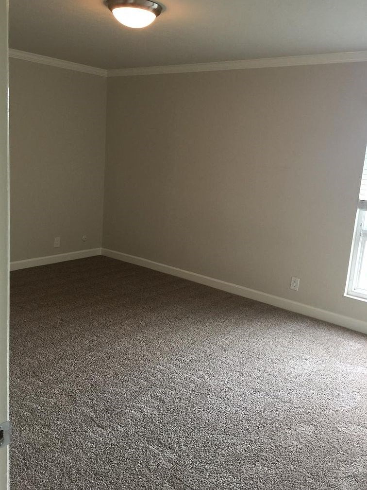 A room with a carpeted floor and a window.