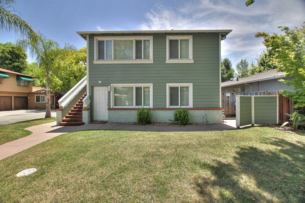 a green house with a lawn and a staircase