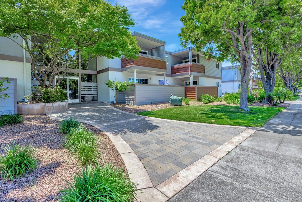 A modern two-story apartment building with a driveway and landscaping.