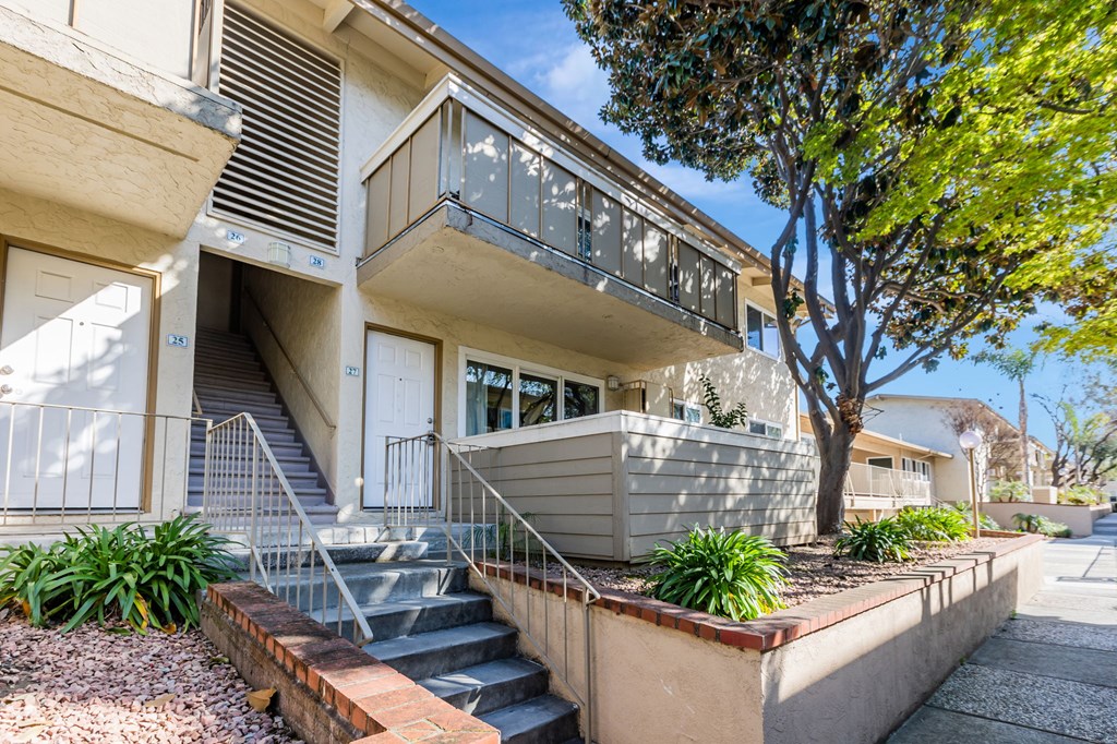 A modern two-story house with a balcony and stairs leading to the entrance.