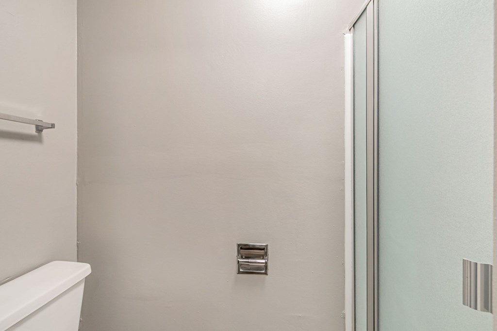 A white toilet in a small bathroom with a glass door.