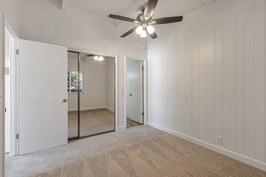 A room with a ceiling fan and carpeted floor.