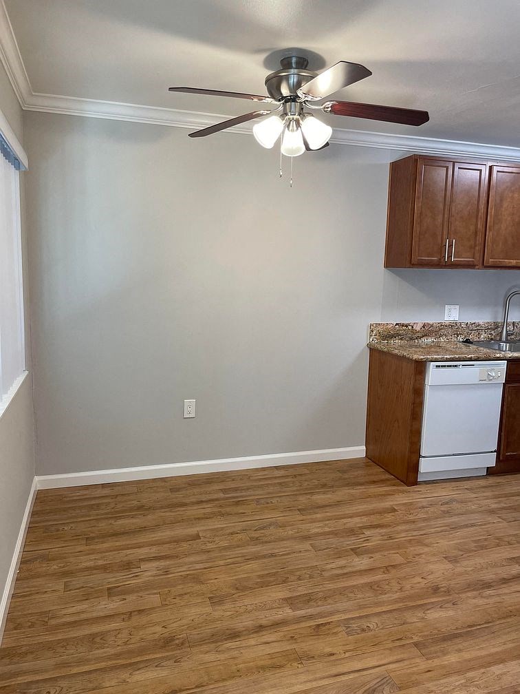 A kitchen with a white dishwasher and wooden cabinets.