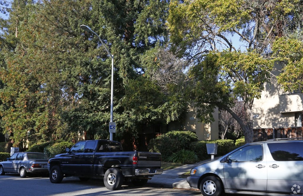 a parking lot with cars and trees in front of a building