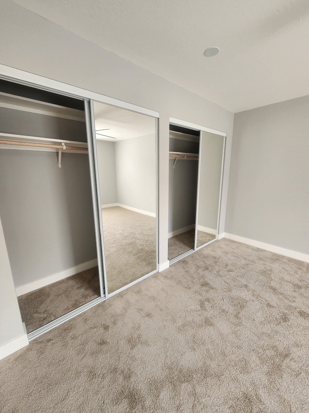 an empty bedroom with mirrored closet doors and carpet
