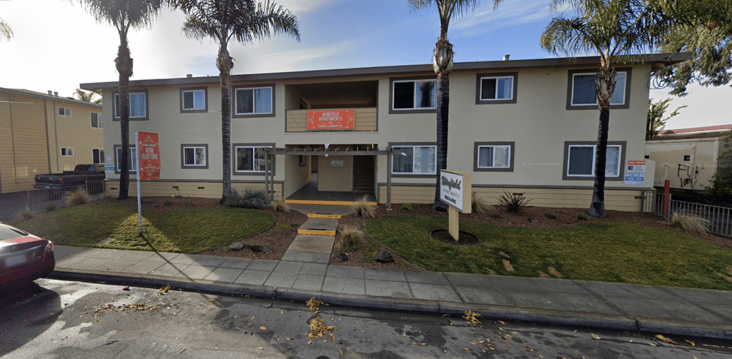 the front of an apartment building with palm trees