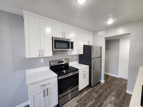 A kitchen with white cabinets and black appliances.
