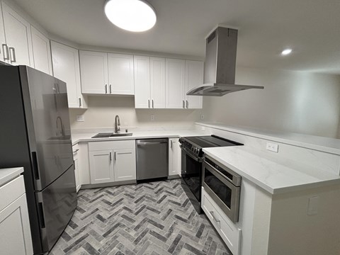 A modern kitchen with a black refrigerator and white cabinets.