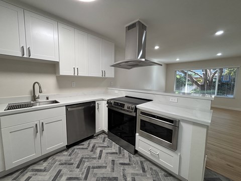A modern kitchen with white cabinets and a black stove top oven.