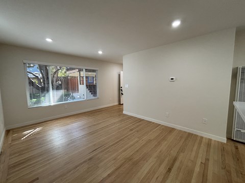 A room with wooden flooring and a window with blinds.