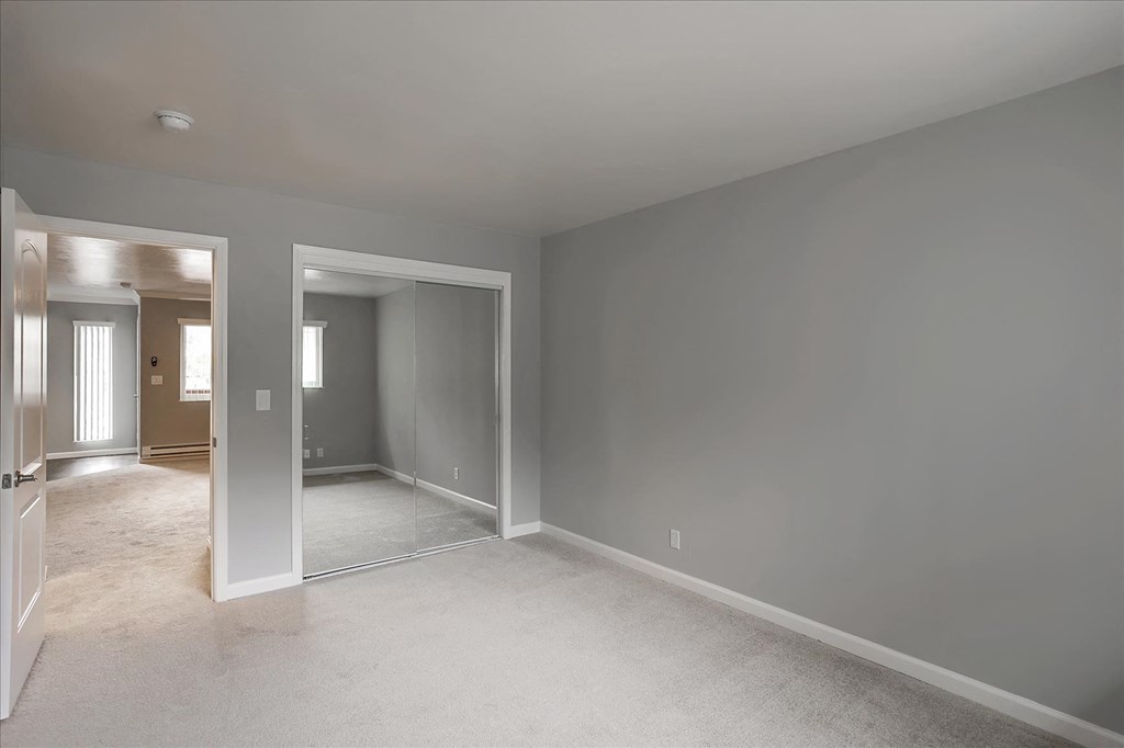 A large empty room with a carpeted floor and white walls.