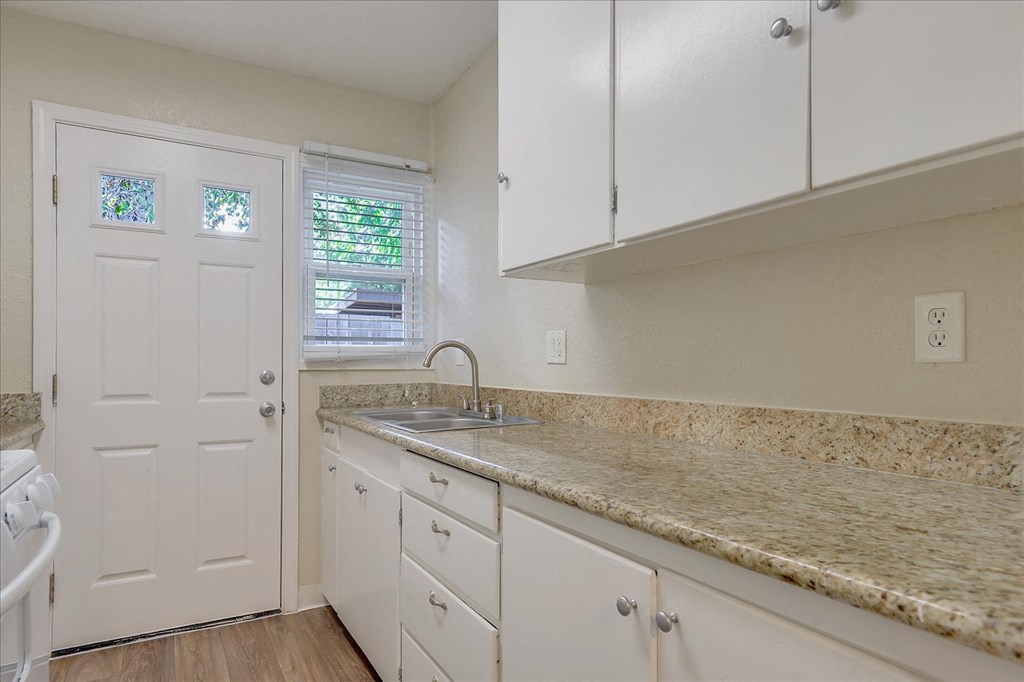 a kitchen with white cabinets and granite counter tops and a sink