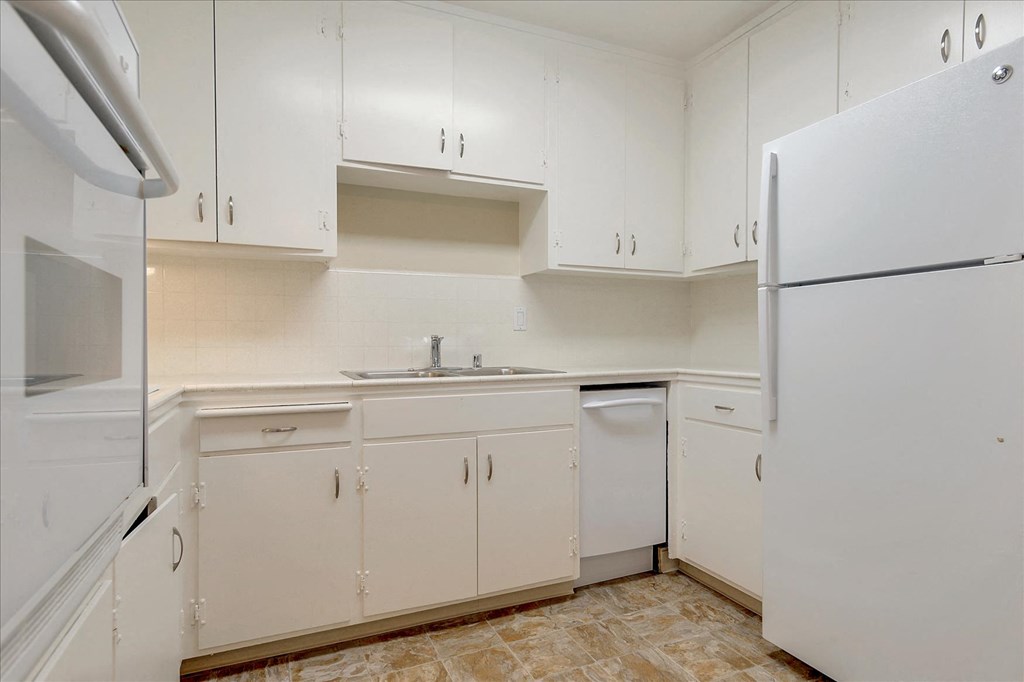 A kitchen with white cabinets and appliances.