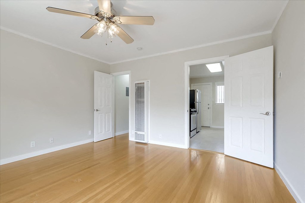 A room with a ceiling fan and wooden floors.